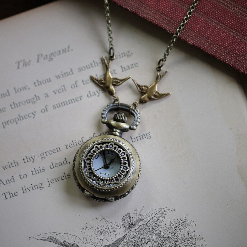 Antiqued brass pocket watch with a Lace Circlet design. This watch is attached to birds connected to a brass chain.