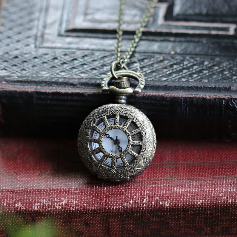 Antiqued brass pocket watch with a Sun Window design. This watch is attached to a simple brass chain.