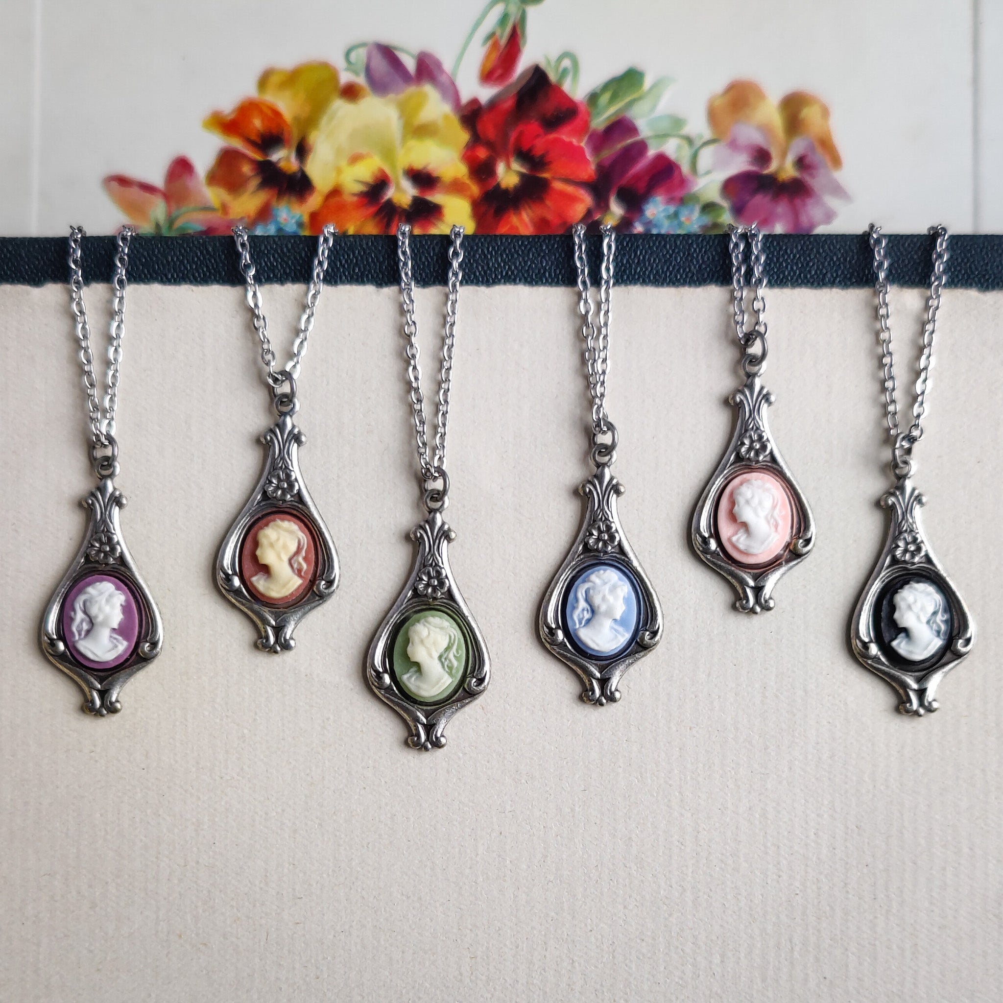 Antiqued silver necklaces with purple, orange, green, blue, pink, and black cameos of women on filigree drop settings.