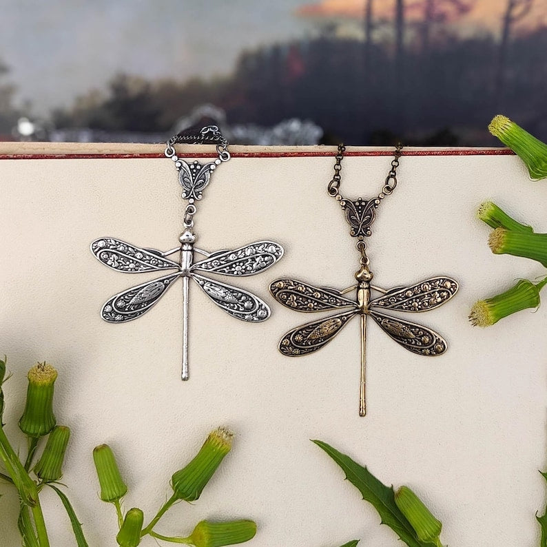 Antiqued silver and brass dragonfly pendants with ornate art nouveau connecters side-by-side.