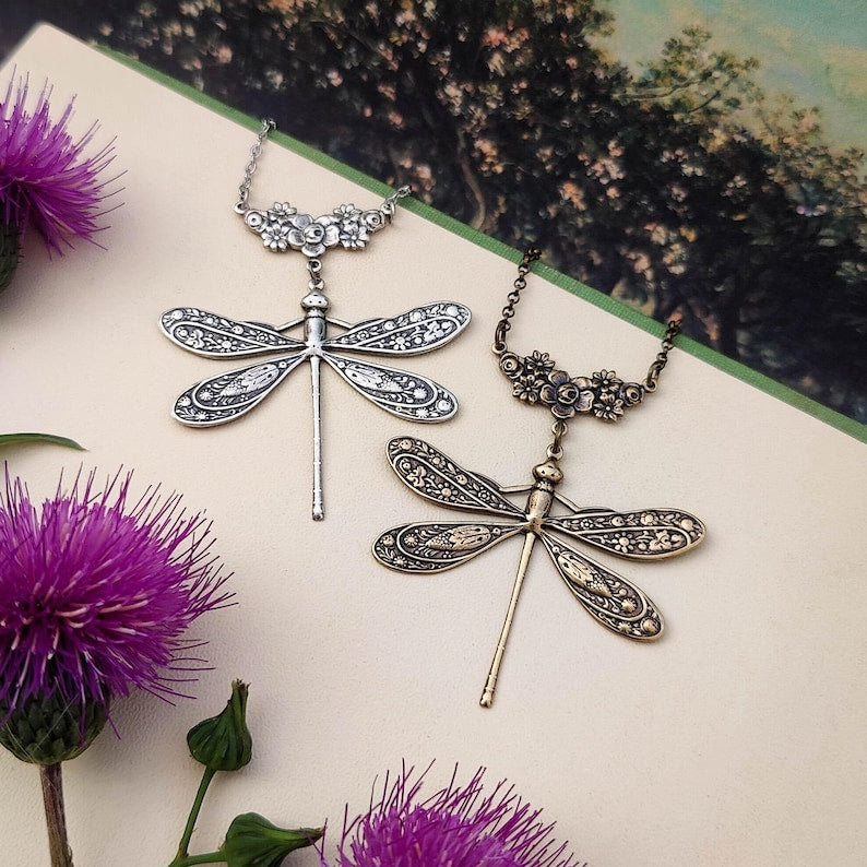 Antiqued silver and brass dragonfly pendants with ornate garden connecters side-by-side.