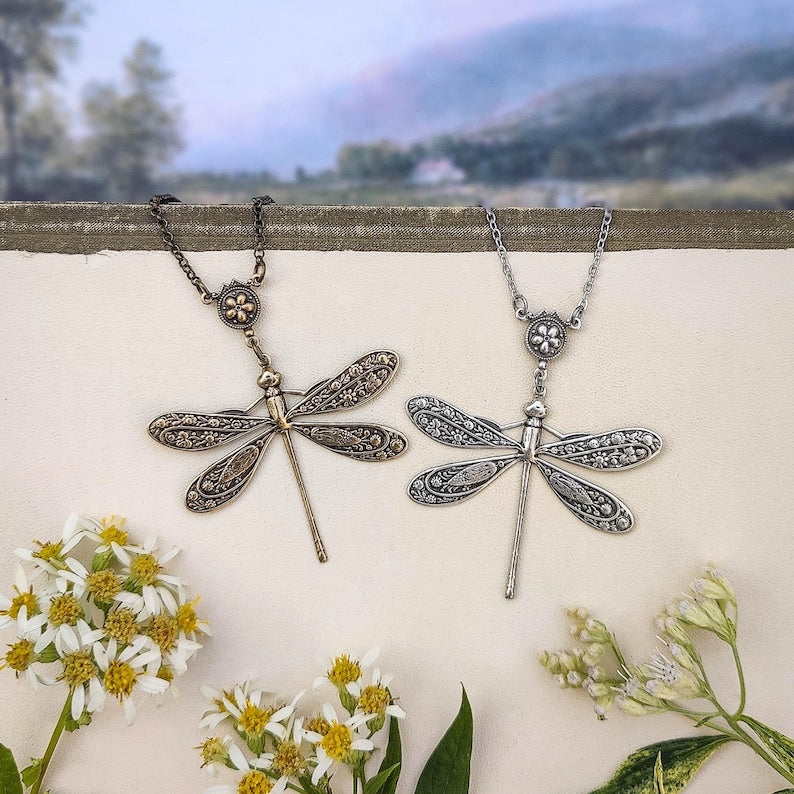 Antiqued silver and brass dragonfly pendants with ornate sand dollar connecters side-by-side.