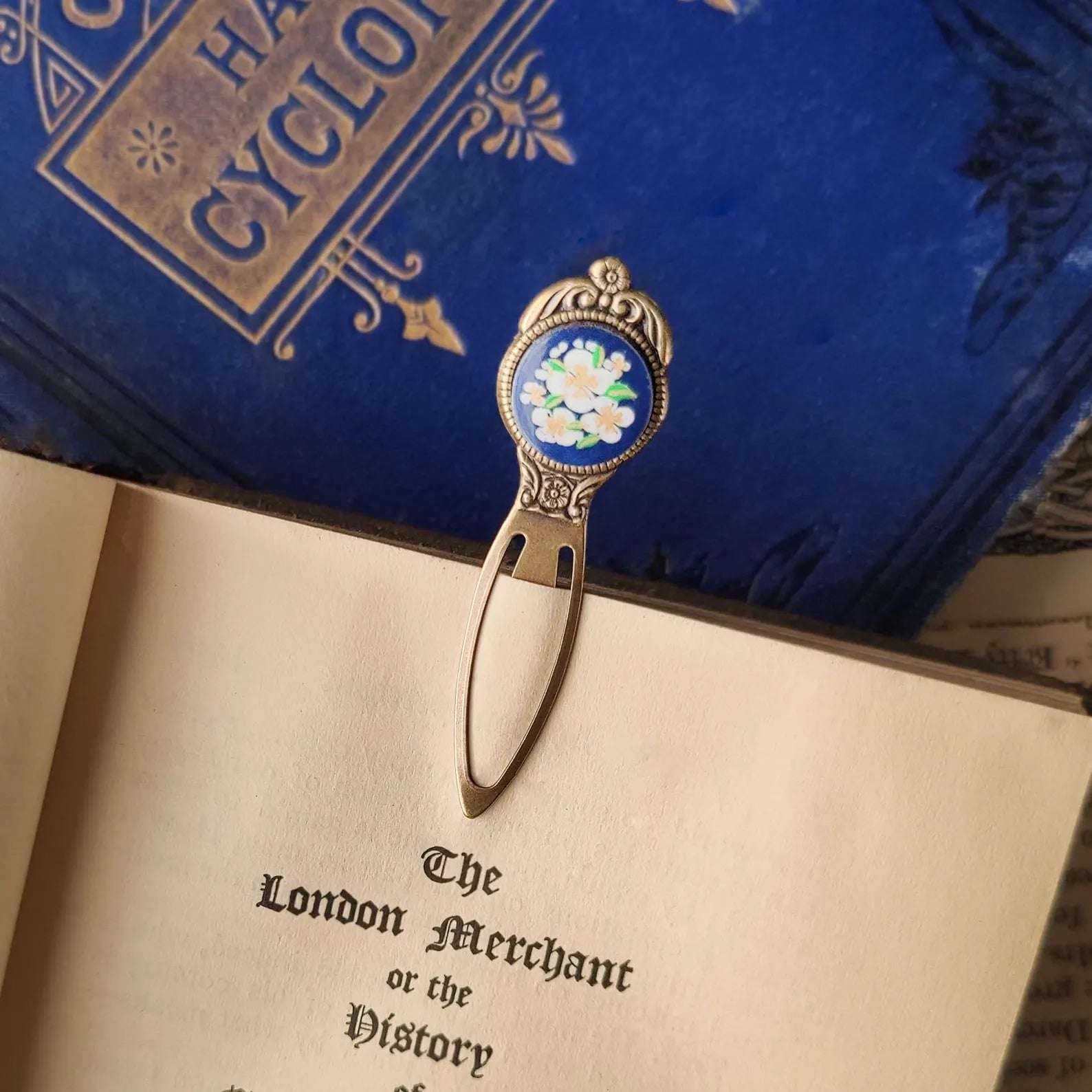 antiqued brass modern vintage inspired bookmark clip page saver with a circle metal blue flower motif a perfect gift for an author.