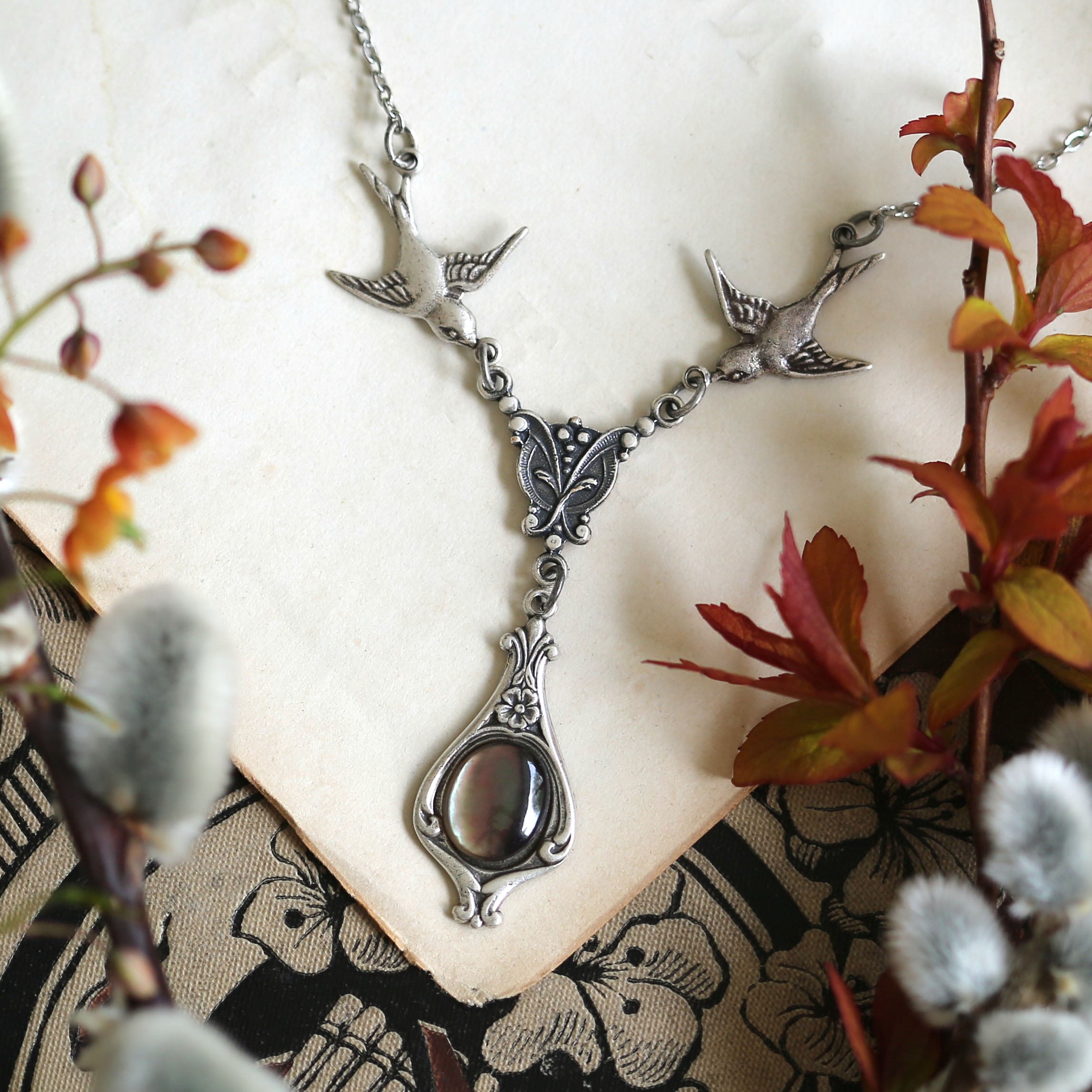 Silver vintage-style necklace with two birds and a gray shell drop
