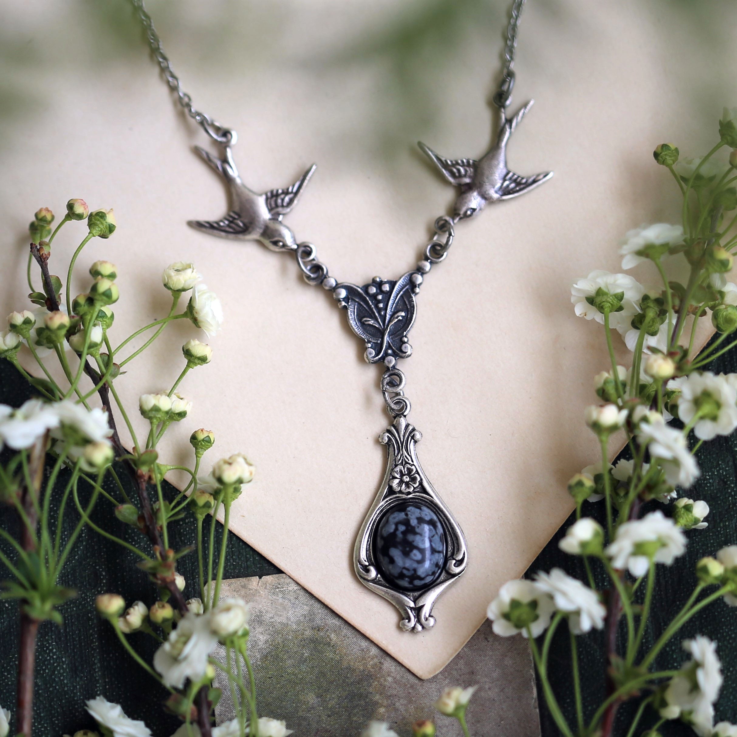 Silver vintage-style necklace with two birds and a black snowflake obsidian drop