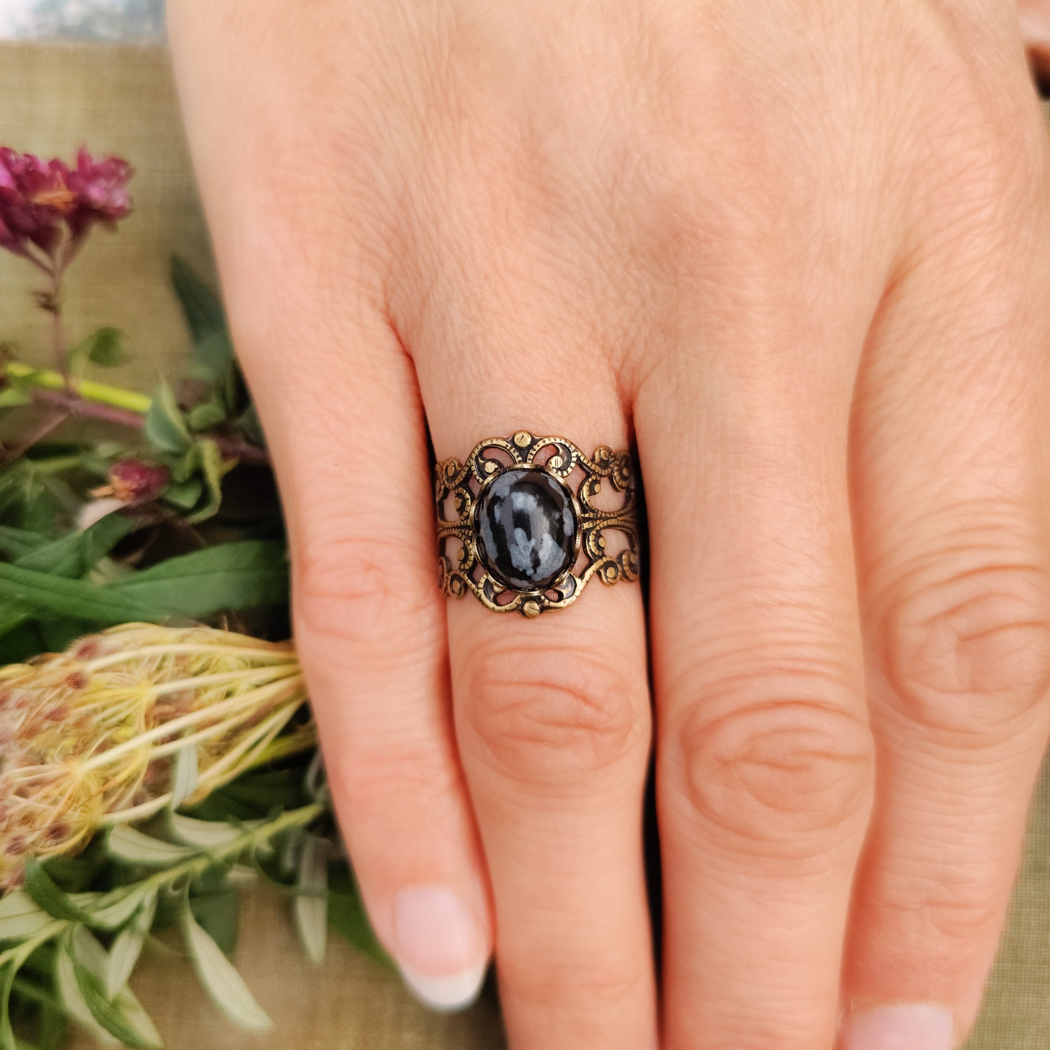 rich antiqued brass modern vintage inspired adjustable filigree ring with a dark black and gray mottled snowflake obsidian oval semi-precious mineral stone set in a romantic academia aesthetic