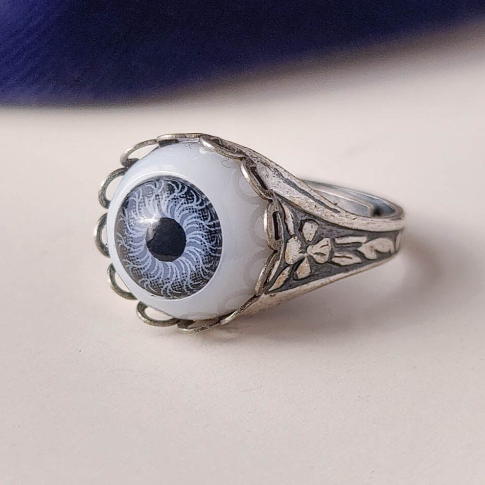 antiqued silver victorian gothic adjustable otherworldly lovecraft cocktail ring with a light blue doll's evil eye.
