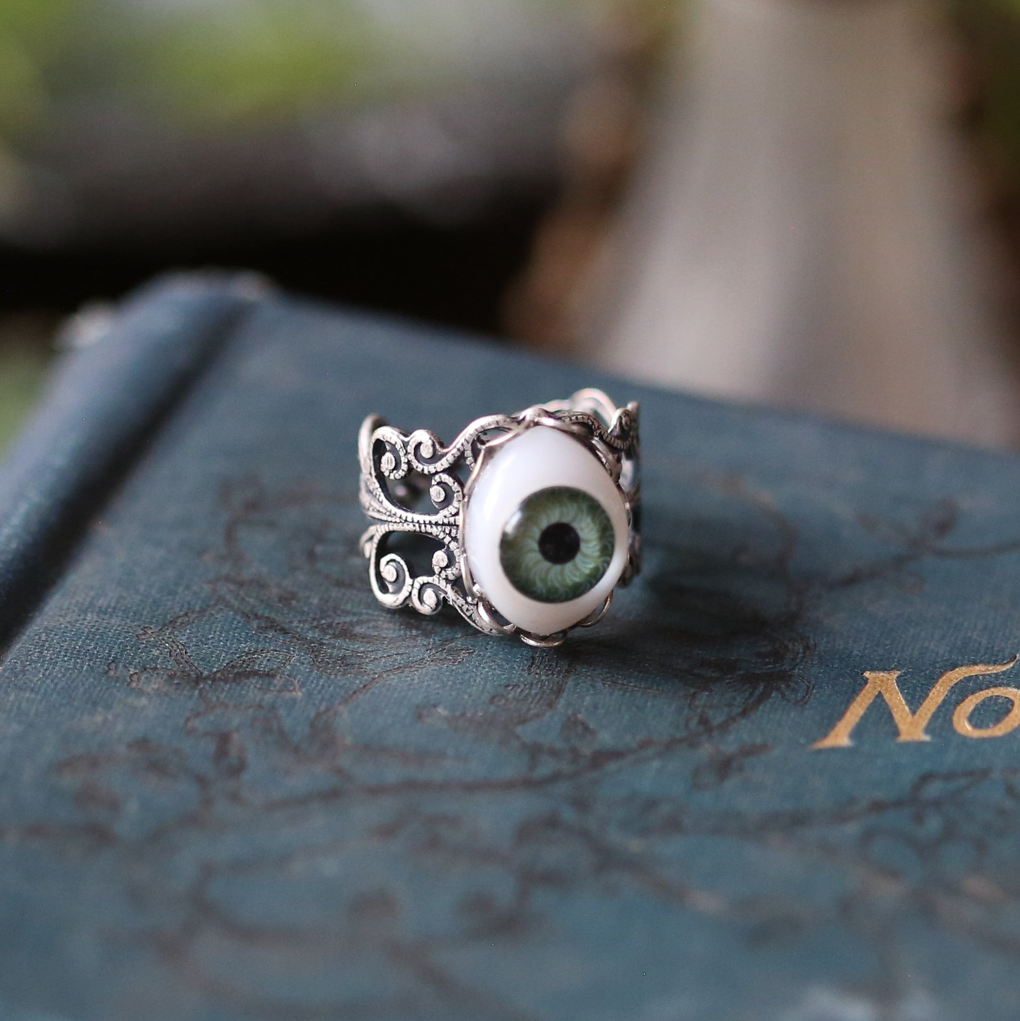 vintage style antiqued silver resizeable filigree ring with a green oval doll's eye in victorian gothic style