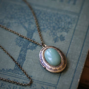 Antiqued brass oval stone locket necklace in vintage style with green aventurine mineral.