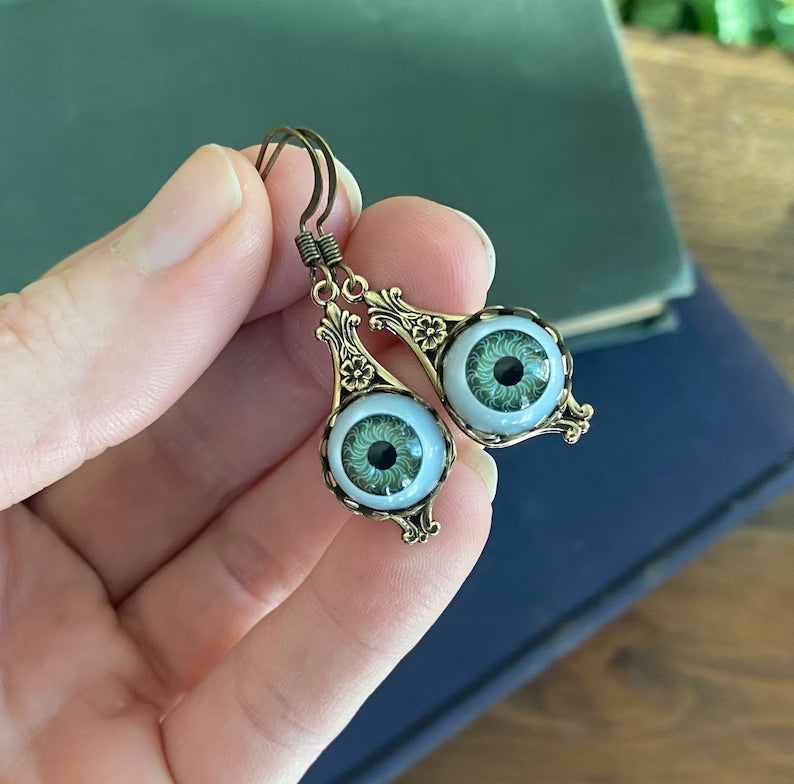 Antiqued brass dangle earrings in the vintage style with green doll's eyes set in a bezel. Great punk, steam punk, goth, mystic aesthetic
