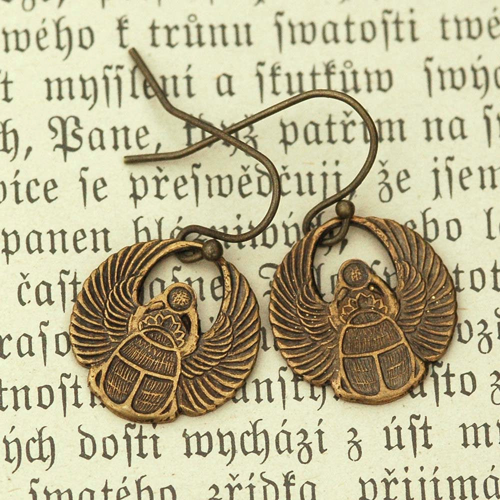 A pair of brass scarab earrings with Art Deco style patterns.