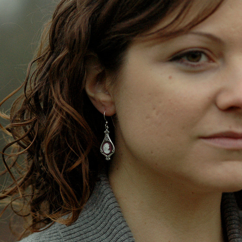 Antiqued silver earrings with purple and white cameos of women on filigree drop settings.