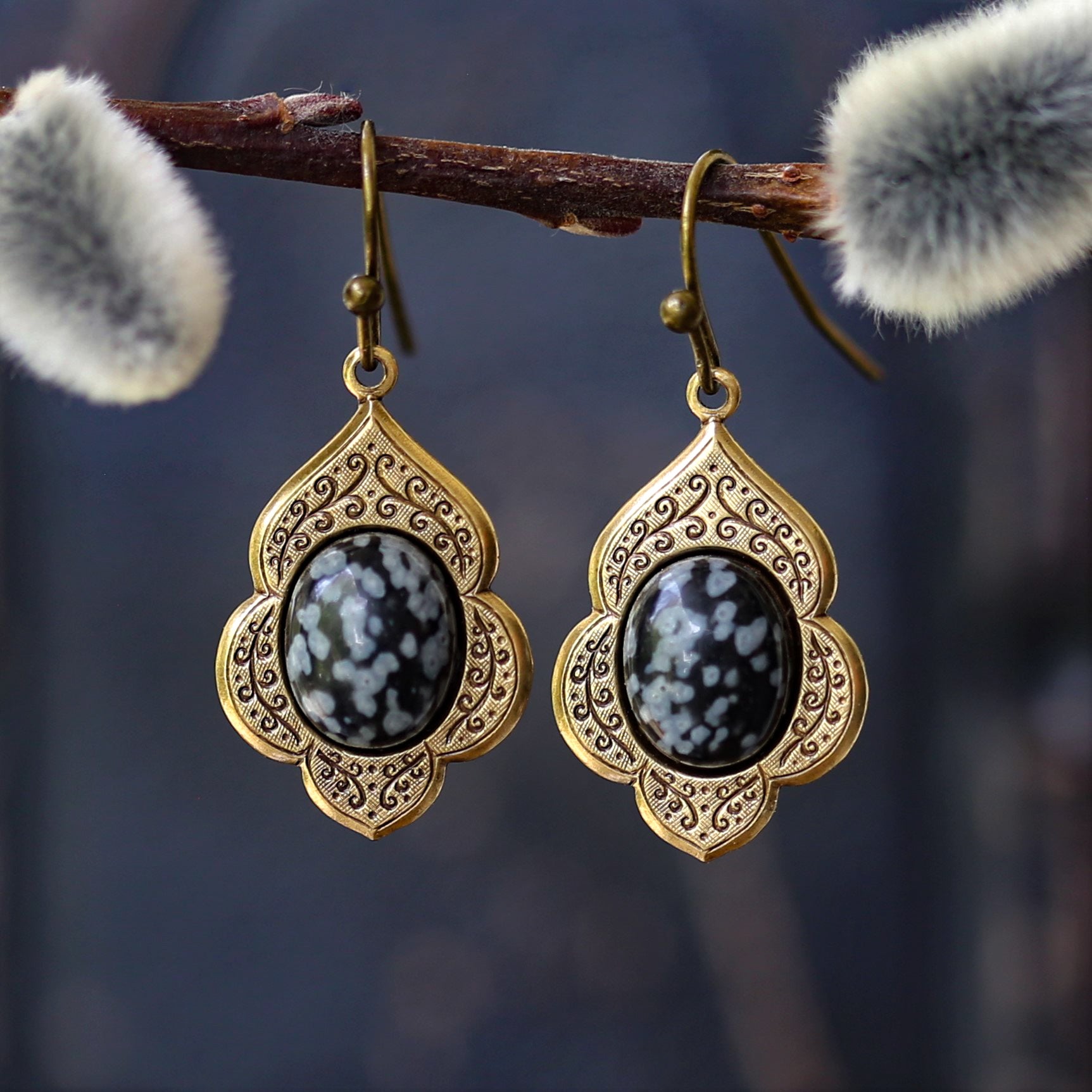 antiqued brass vintage style drop dangle earrings with a leaf and vine motif with semi-precious black and gray snowflake obsidian mineral oval stone cabochons.