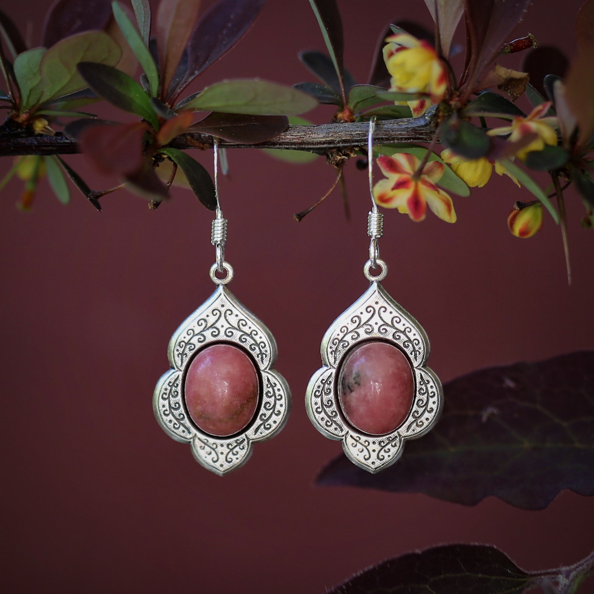 antiqued silver vintage style drop dangle earrings with a leaf and vine motif with semi-precious pink rhodonite mineral oval stone cabochons.