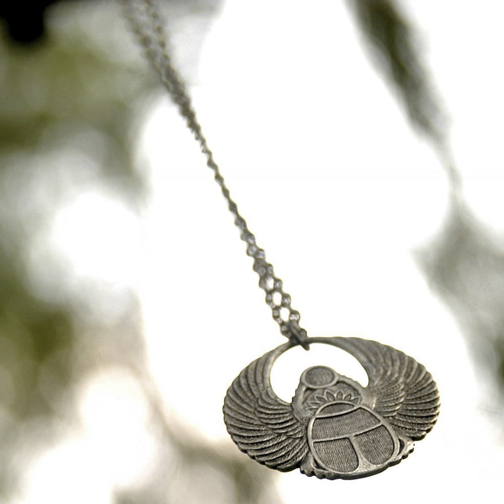Antiqued silver scarab beetle pendant on a simple chain. Pendant is in a circular Art Deco design.