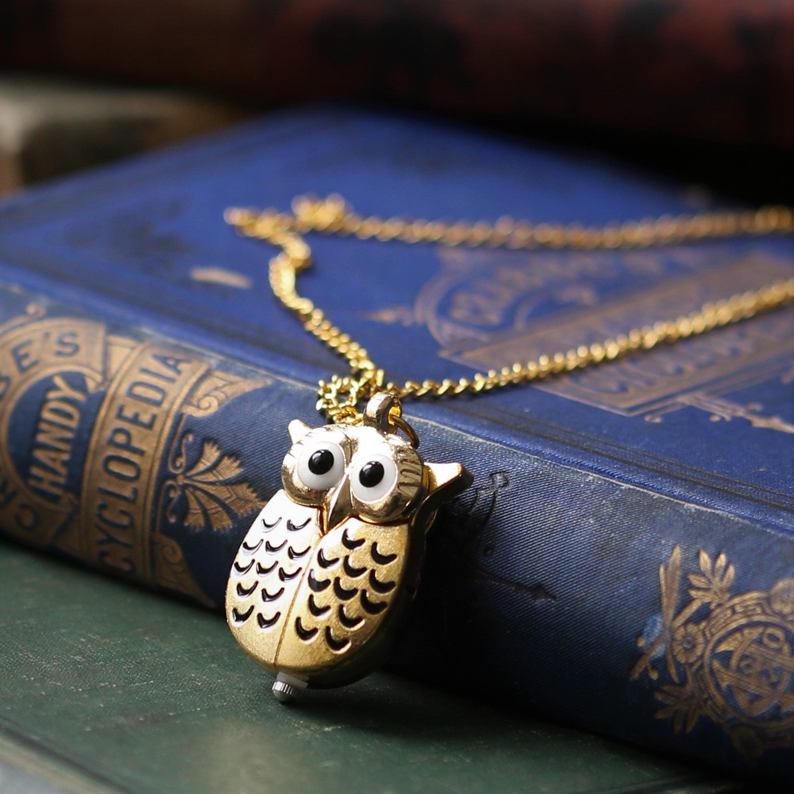A Gold owl-shaped watch necklace. This watch is closed with the owl's wings covering the watch face.