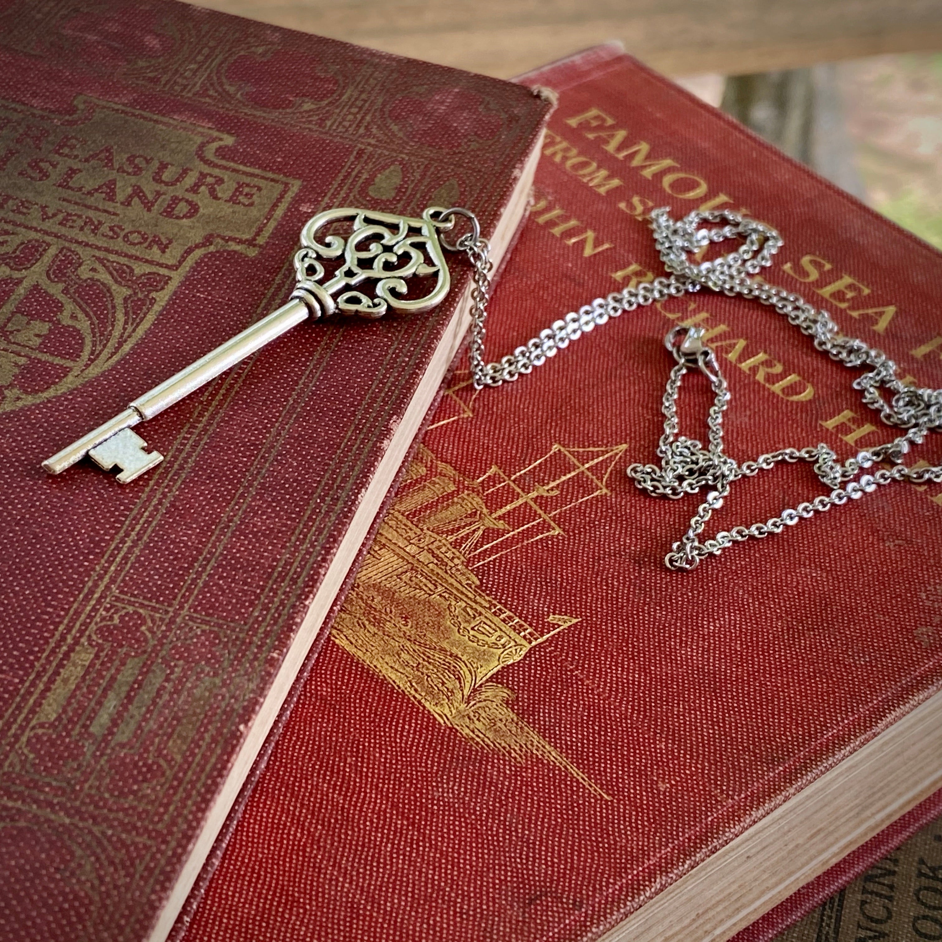 Antiqued brass key pendant necklace. The head of the key is shaped like an ornate upside down heart with two 'c's facing each other inside.