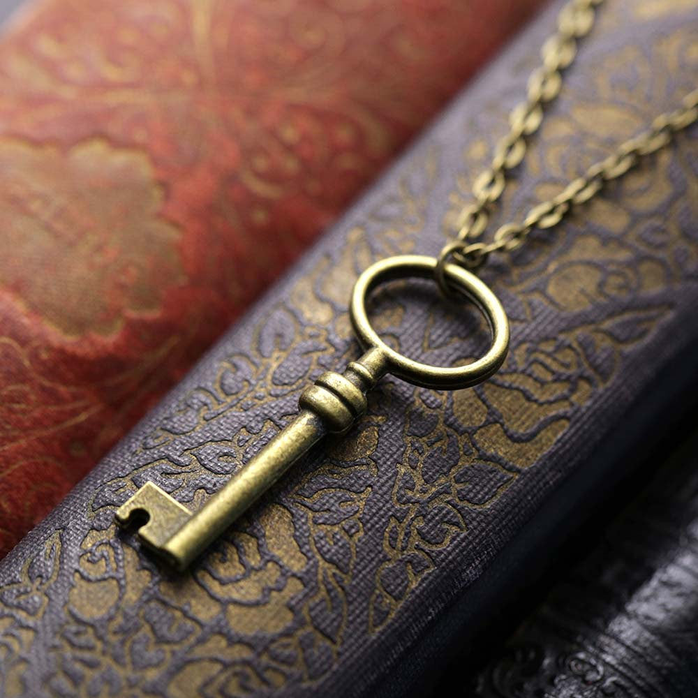 Simple brass key with an oval head on a necklace chain.