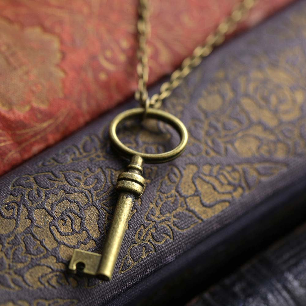 Simple brass key with an oval head on a necklace chain.