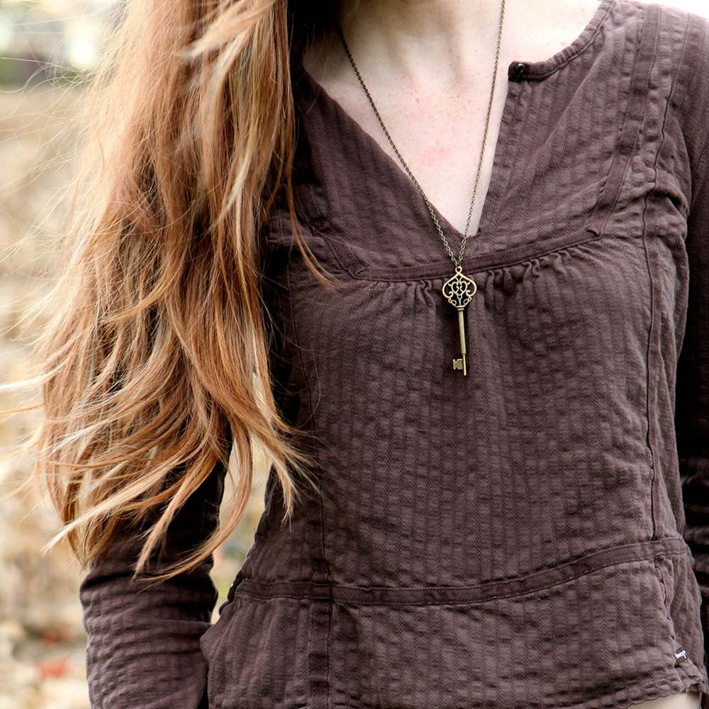 Antiqued brass key pendant necklace. Displayed on a model.