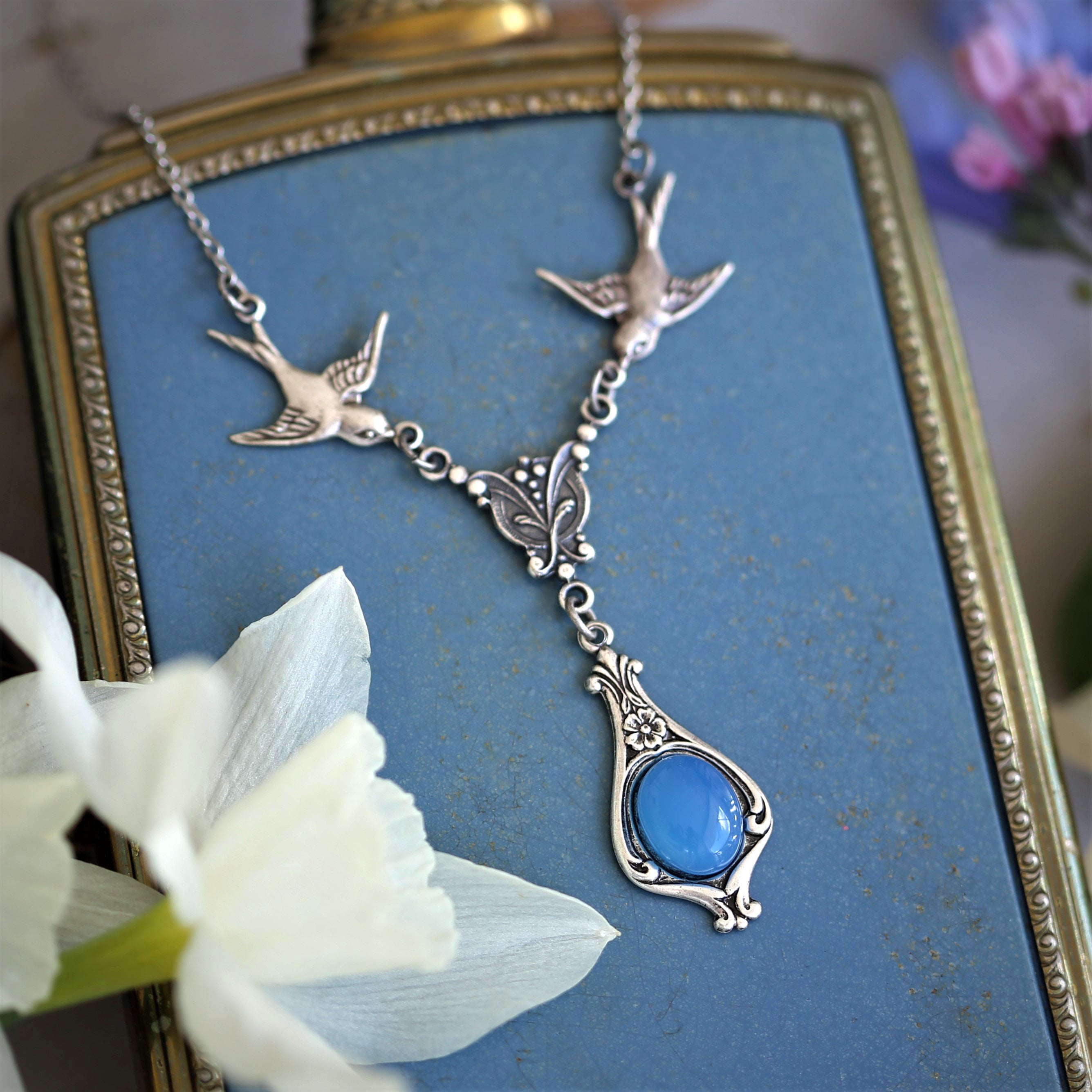 Antiqued silver vintage-style blue agate drop pendant featuring birds in a winter academia style.