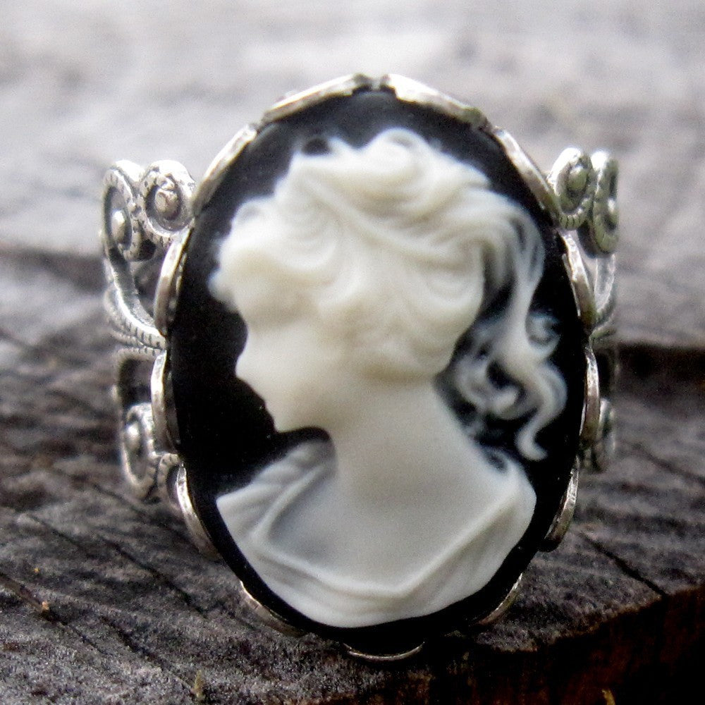 A cameo ring with a white woman on a black background. This oval cameo is set on an adjustable silver filigree ring.