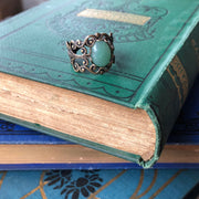 Antiqued brass adjustable vintage style filigree stone ring with green oval mineral.