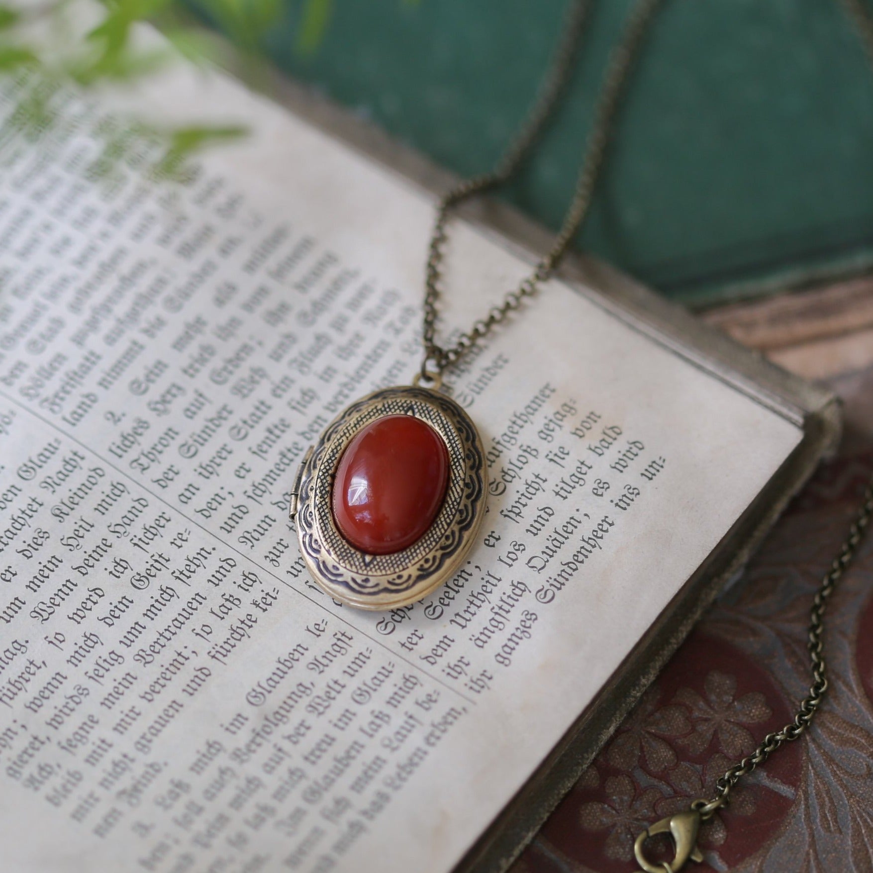 Antiqued brass reenactment long oval carmine orange carnelian semi-precious stone mineral locket in bold autumnal art academia style making a great sentimental gift for your loved one.