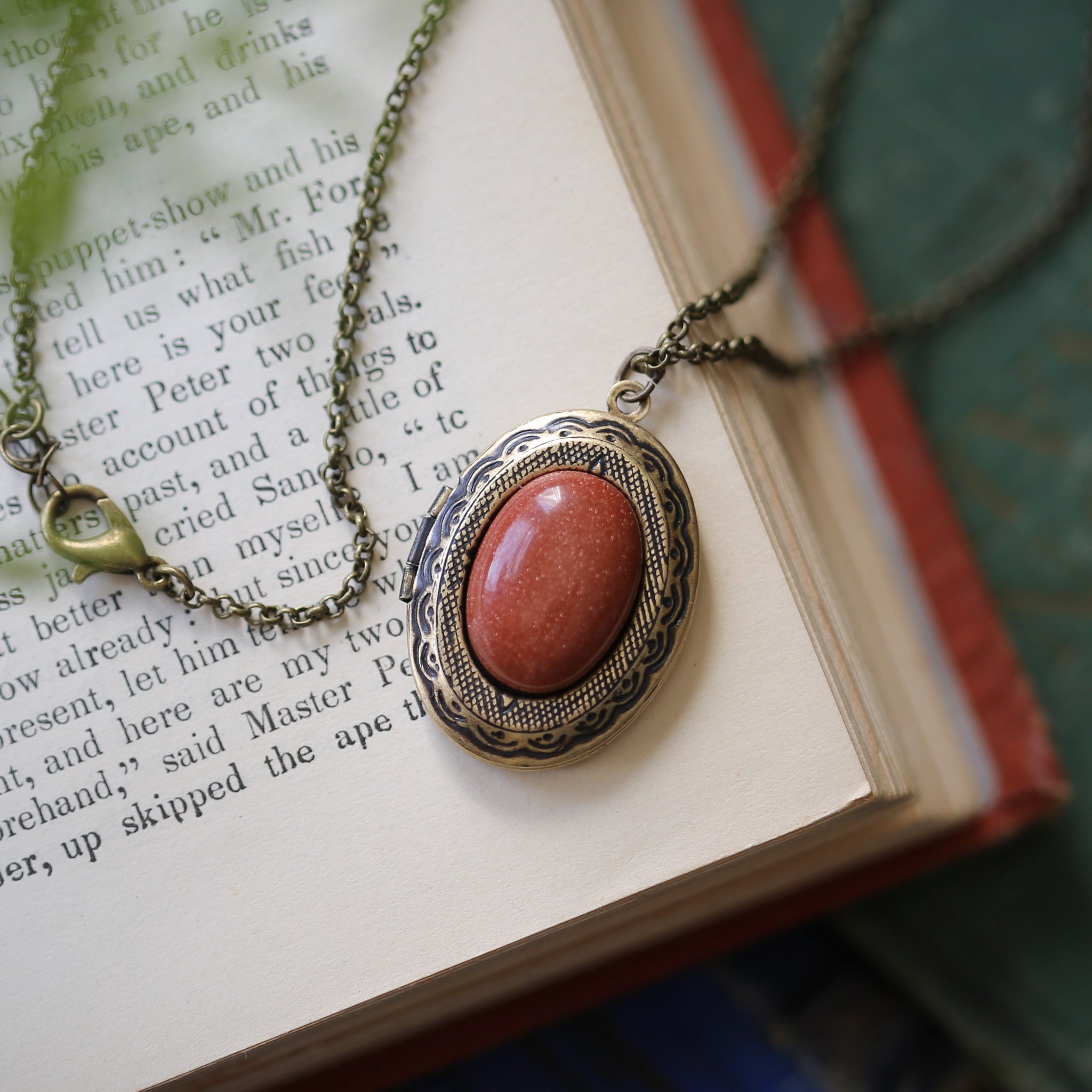 Antiqued brass eye-catching long oval orange goldstone semi-precious stone mineral locket in bold autumnal art academia style making a great sentimental gift for your loved one.