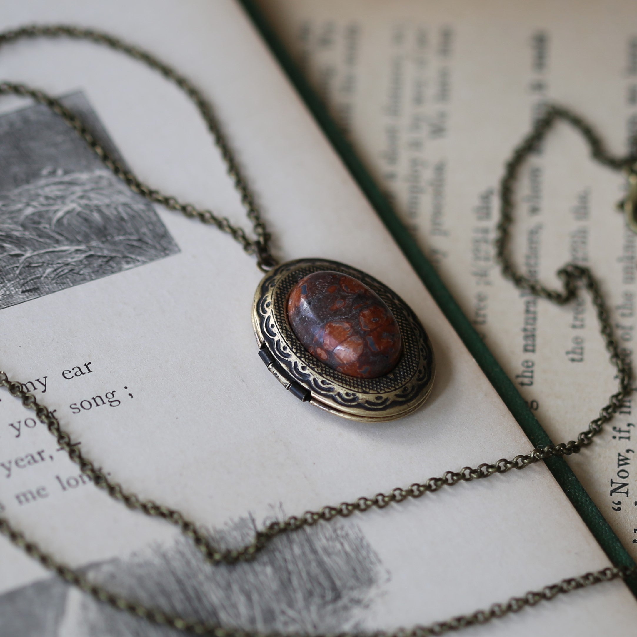 Antiqued brass old world long oval mottled orange and burgundy leopardskin jasper semi-precious stone mineral locket in bold bronzepunk style making a great sentimental gift for your loved one.