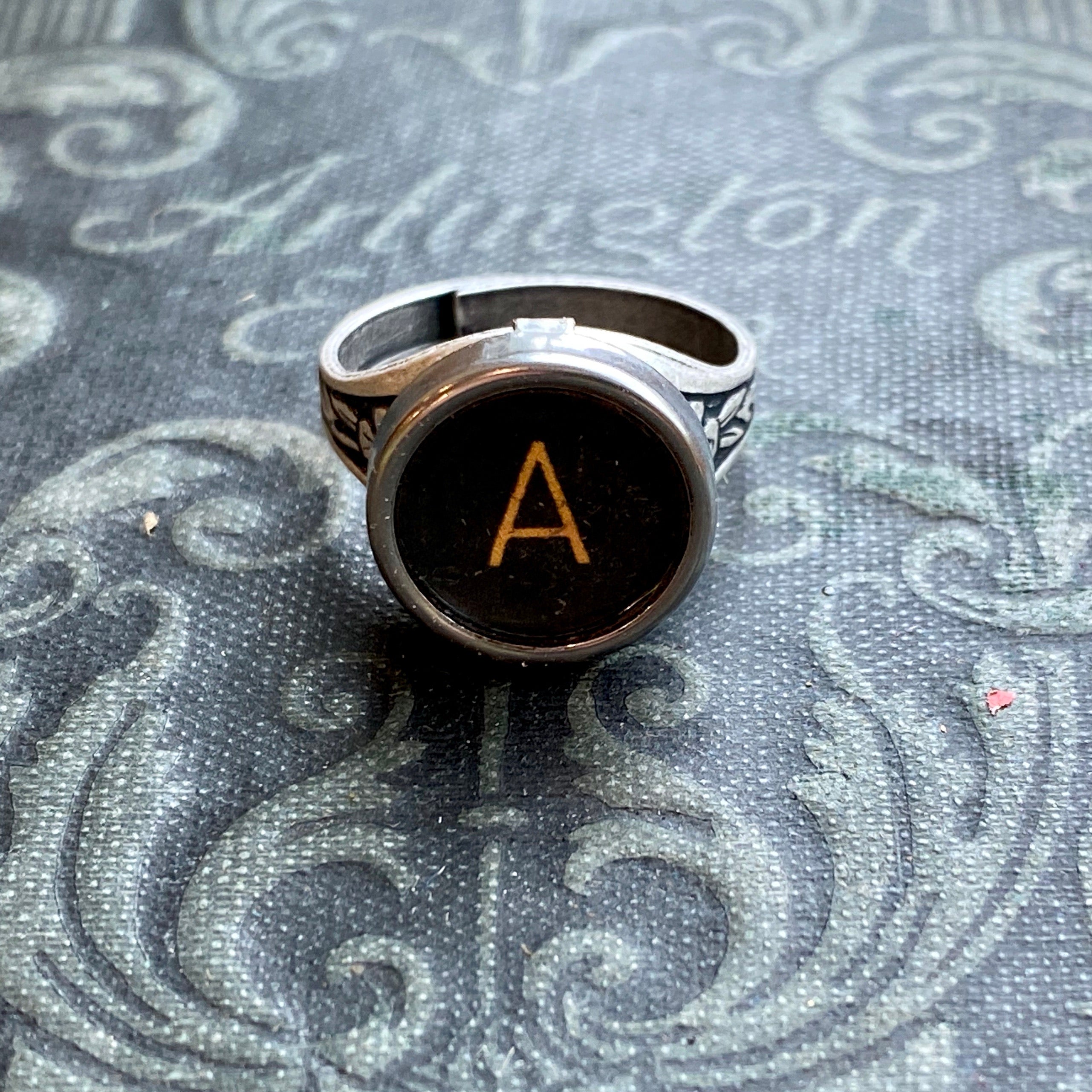 Silver adjustable ring with an authentic vintage typewriter key as the centerpiece. The key is metal-rimmed with glass covering an off-white letter 'A' on a black background.