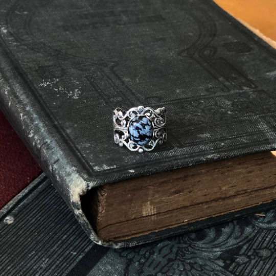rich antiqued silver modern vintage inspired adjustable filigree ring with a dark black and gray mottled snowflake obsidian oval semi-precious mineral stone set in a witchy aesthetic