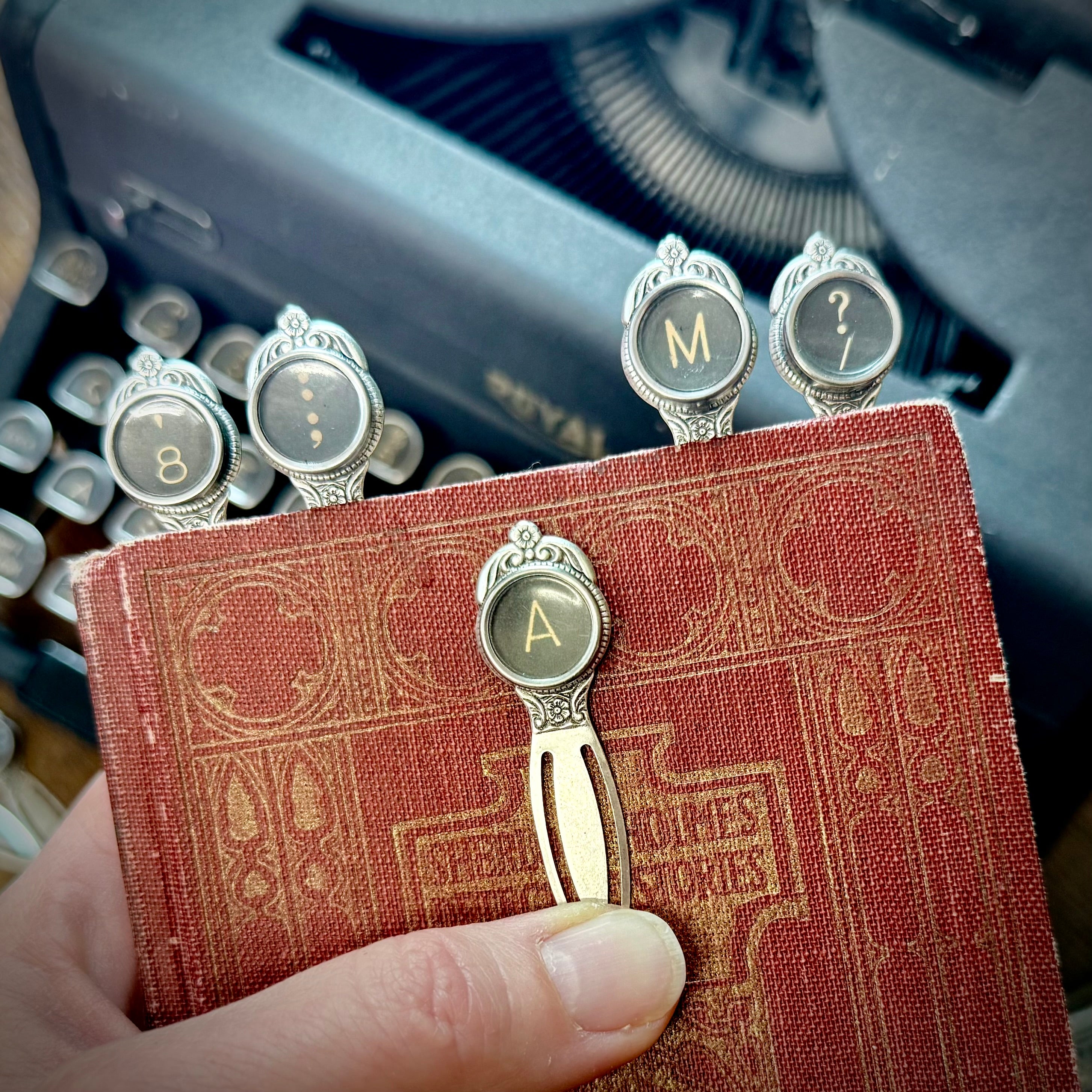 Vintage Typewriter key bookmark metal clip page savers on a small book with a typewriter in the background