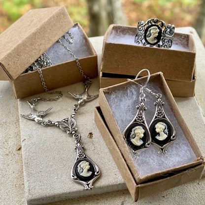A set of black and white lady cameos on silver settings: a ring, a necklace, and earrings.