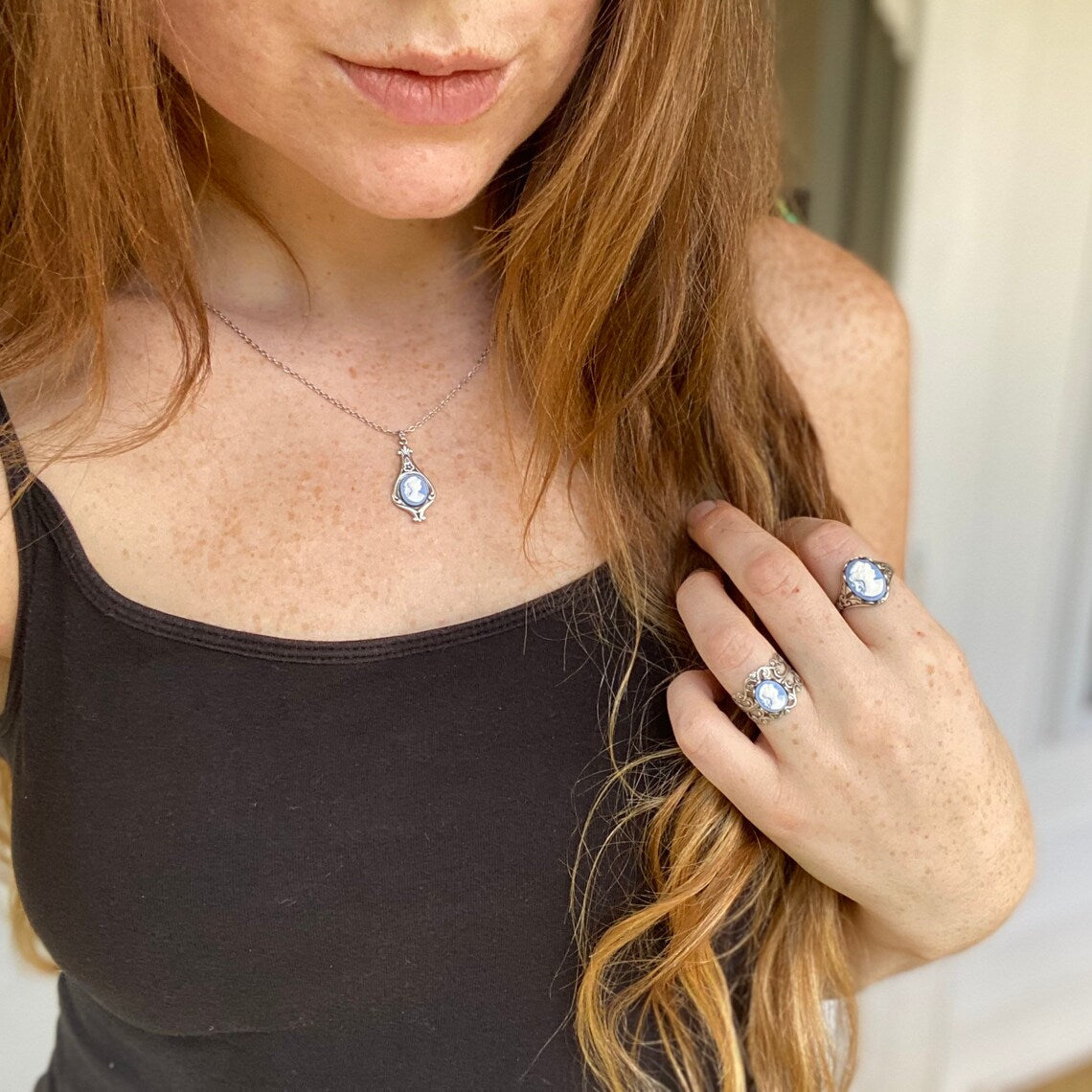 A set of light blue and white lady cameos on silver settings: two rings and a necklace.