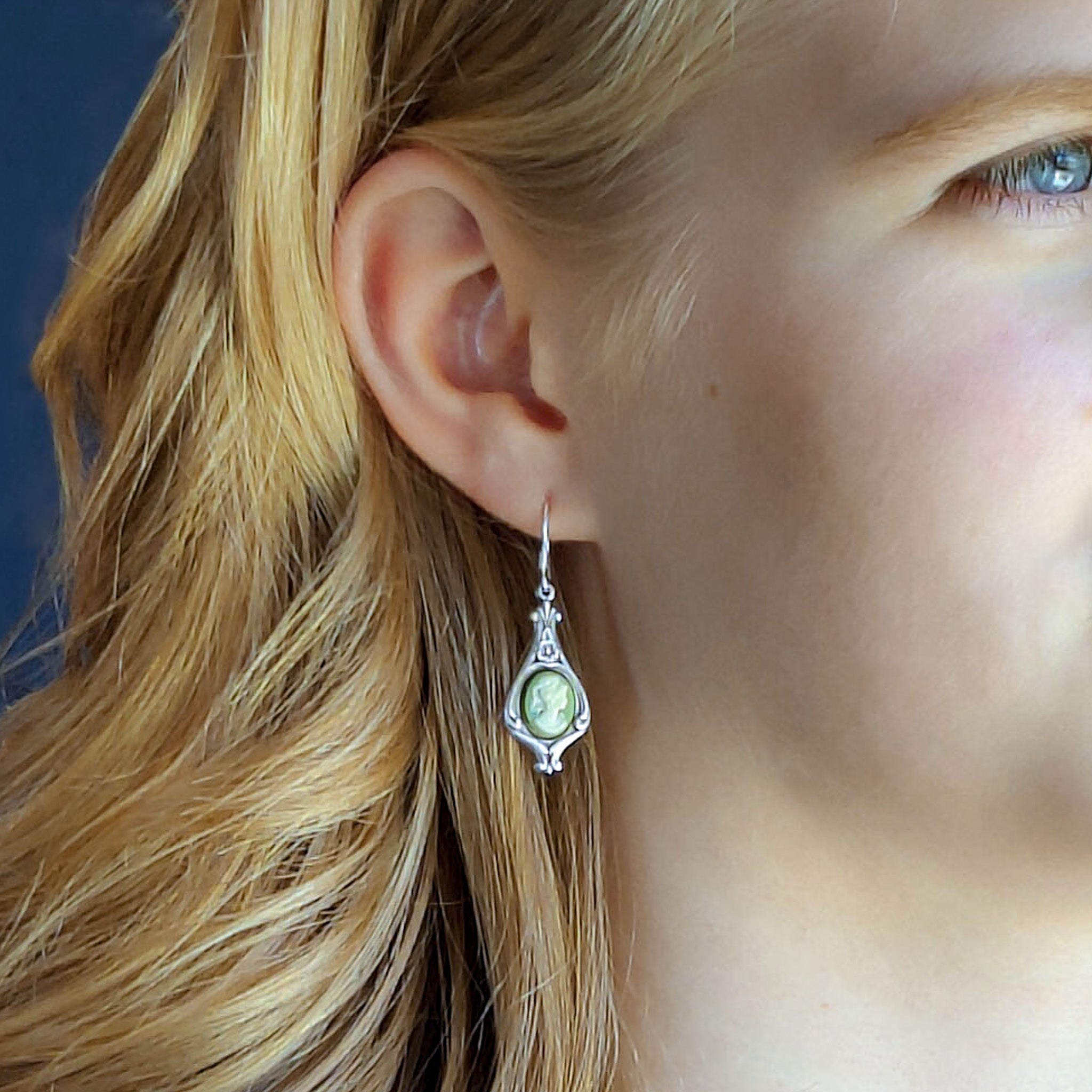 Antiqued silver earrings with green and white cameos of women on filigree drop settings.