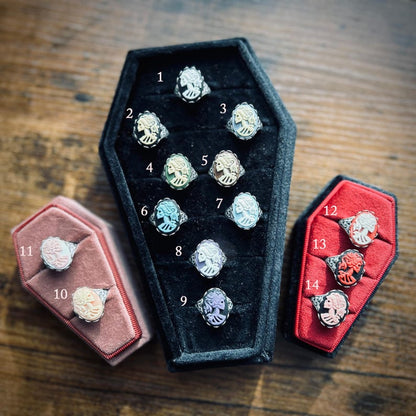 Fourteen skeleton cameo ring options. White skeleton with black, cream with black, cream with blue, cream with green, cream with brown, blue with black, white with blue, white with gray, purple with black, cream with pink, pink with white, white with red, red with black, and pink with black.