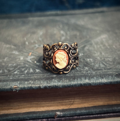 Antiqued brass adjustable filigree ring with orange and cream-colored lady cameo