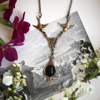 Antiqued brass vintage-style black onyx drop pendant featuring birds in dark gatsby style making a great necklace for a little black dress.