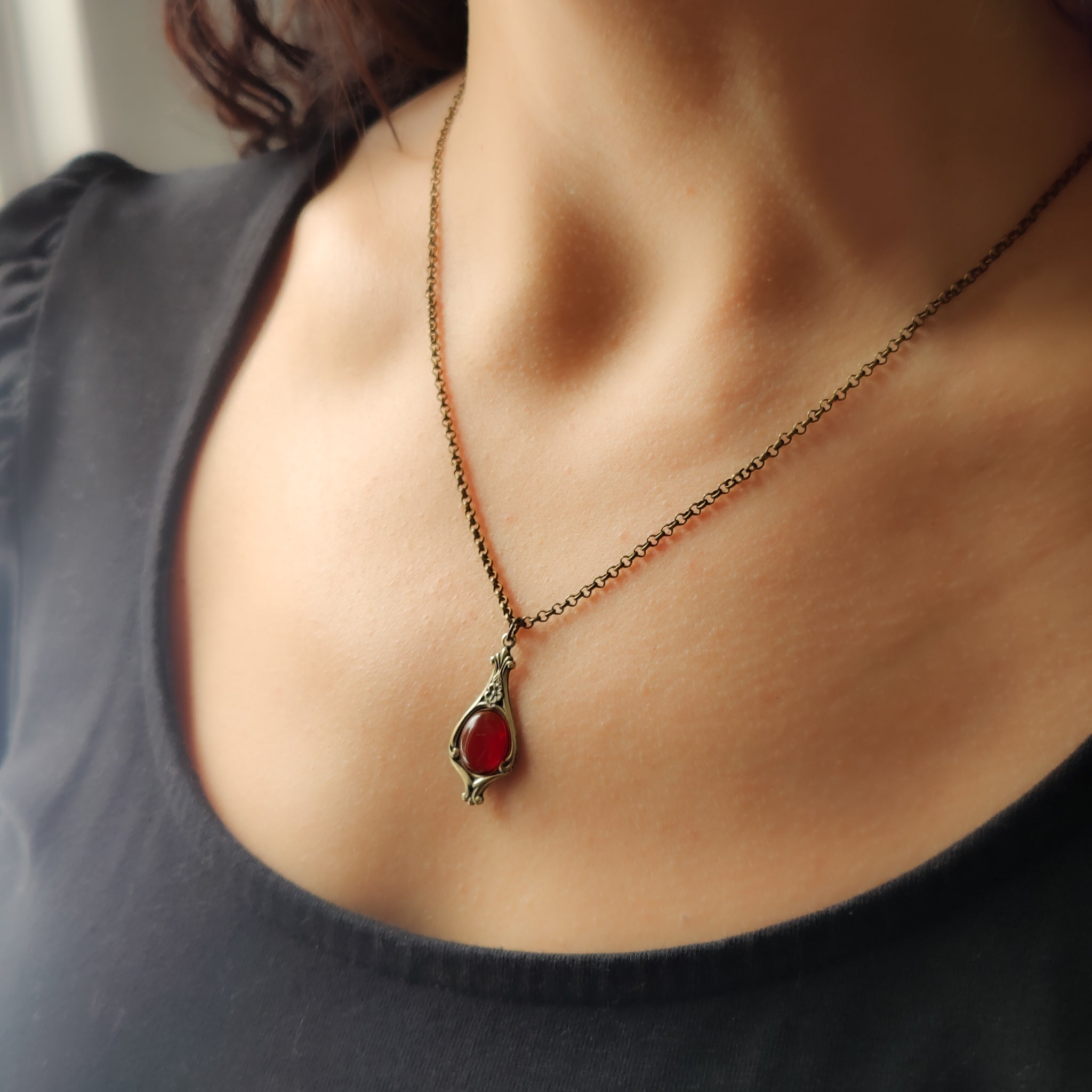 Antiqued brass vintage inspired small autumn academia aesthetic necklace with a dainty orange carnelian stone on a mini floral drop setting.