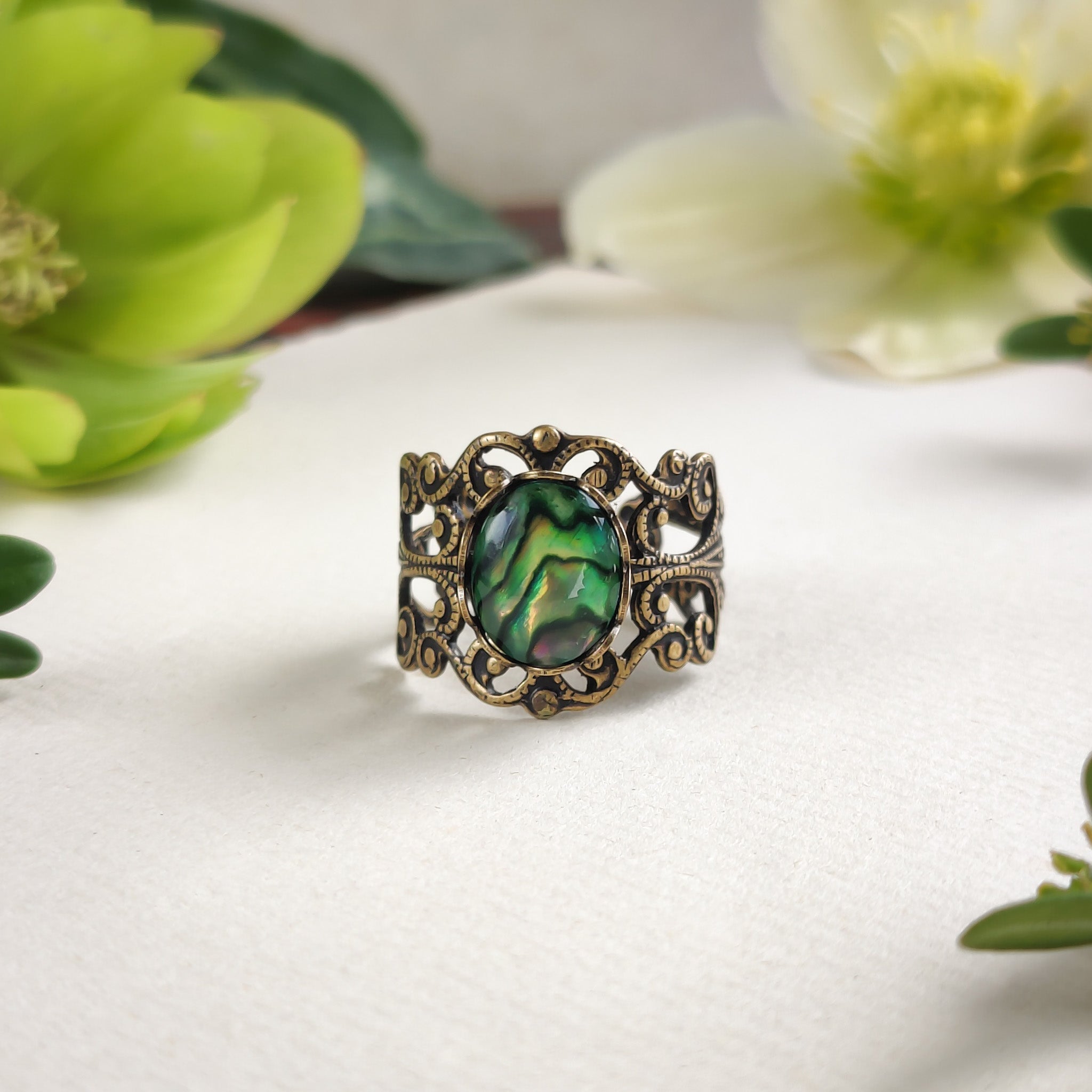 antiqued brass modern vintage style adjustable filigree ring with an iridescent green oval shell in the green academia aesthetic