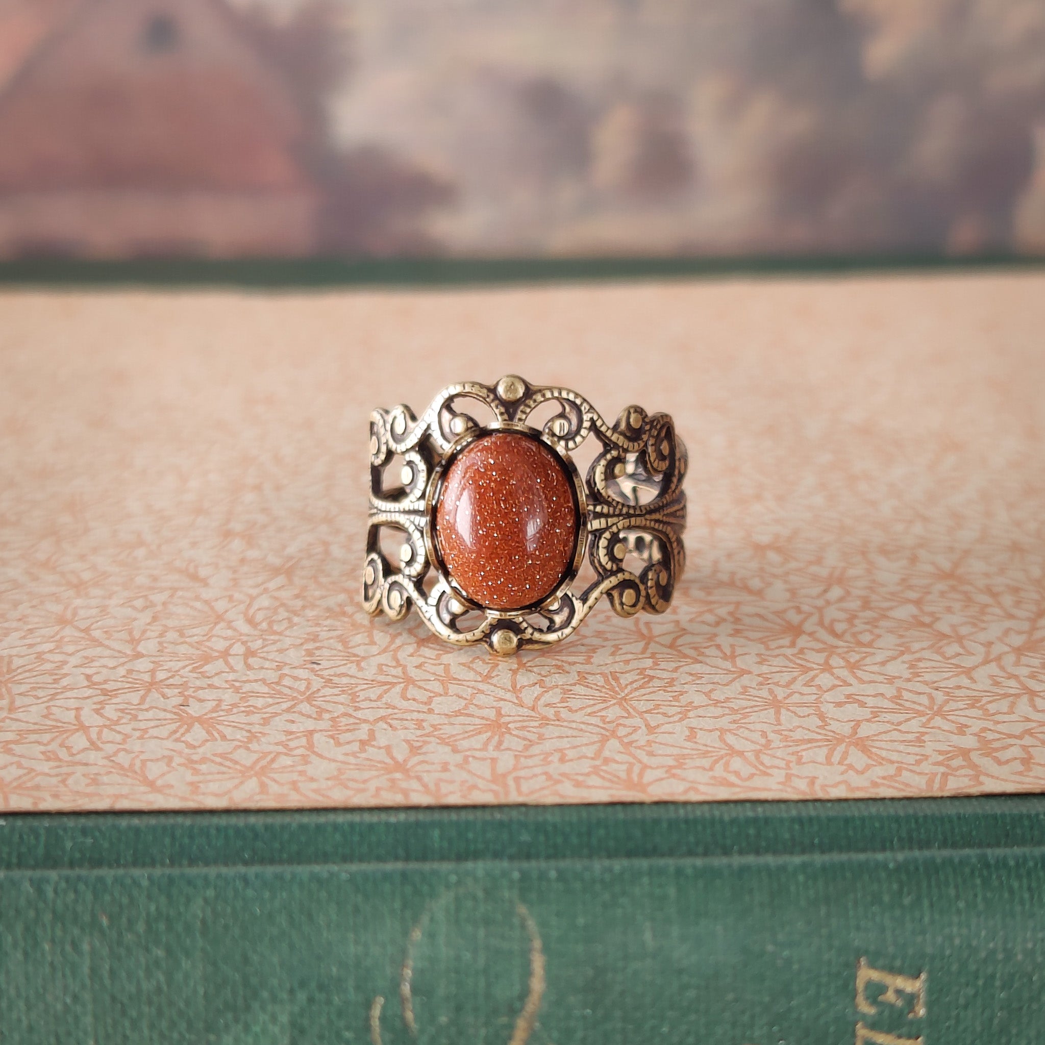 Antiqued brass modern vintage inspired adjustable filigree ring set with an orange goldstone semi-precious mineral in old fashioned aesthetic