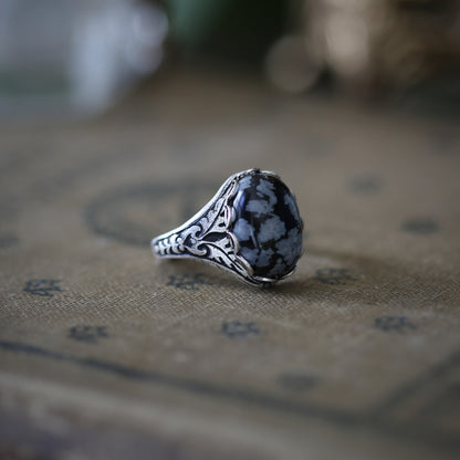 antiqued silver vintage-stye adjustable cocktail ring with black and grey snowflake obsidian oval stone cabochon in dark folk style