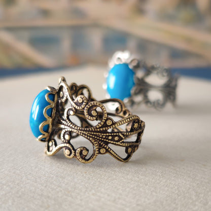 antiqued brass modern vintage inspired resizable filigree statement ring with a turquoise blue howlite oval semi-precious mineral stone in the western fashion aesthetic.