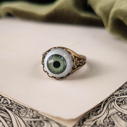 antiqued brass victorian gothic adjustable otherworldly spooky statement ring with a green doll's evil eye.