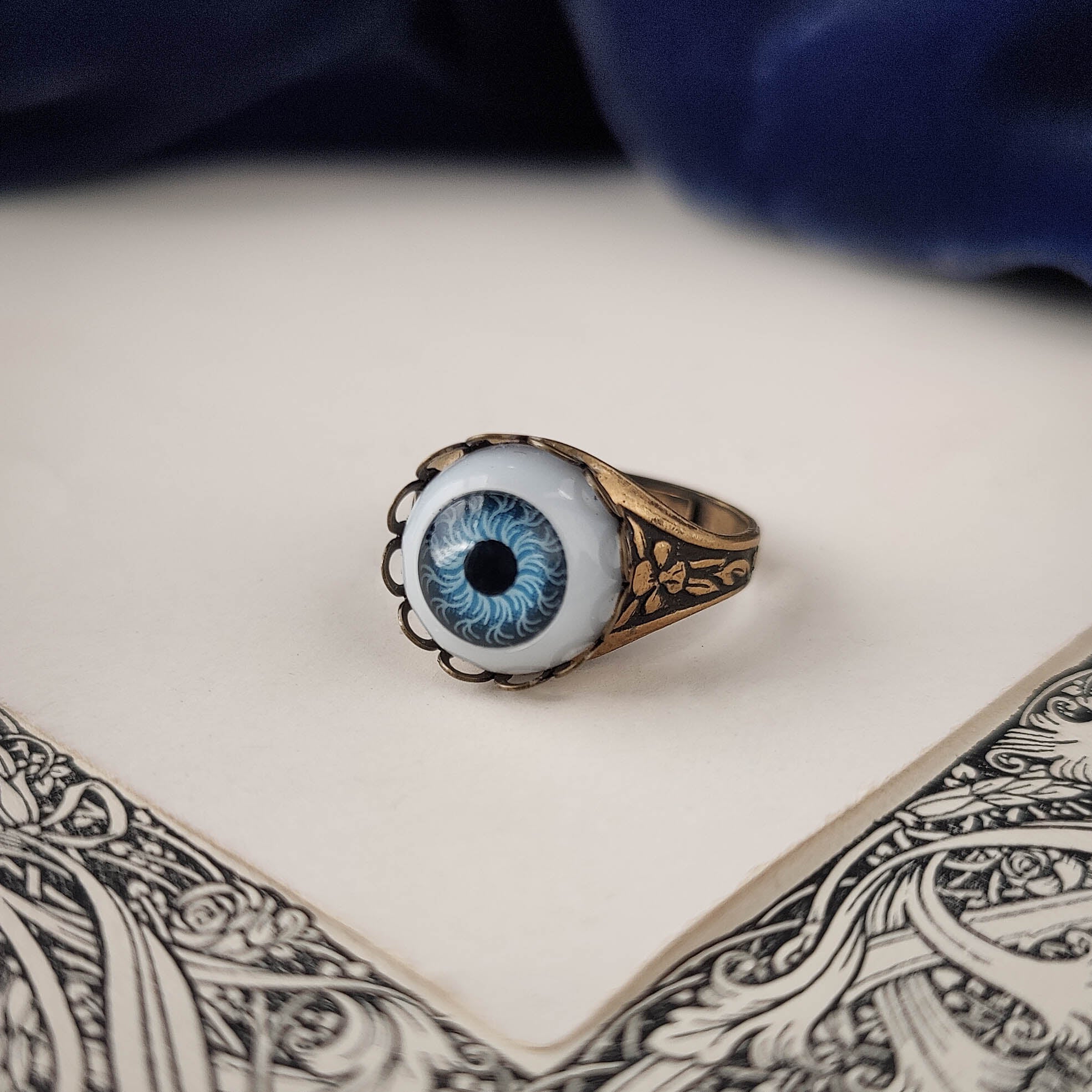 antiqued brass victorian gothic adjustable otherworldly spooky cocktail ring with a light blue doll's evil eye.