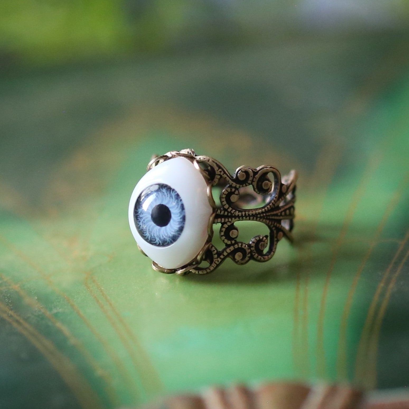 vintage style antiqued brass adjustable filigree ring with a blue oval evil eye in goth style