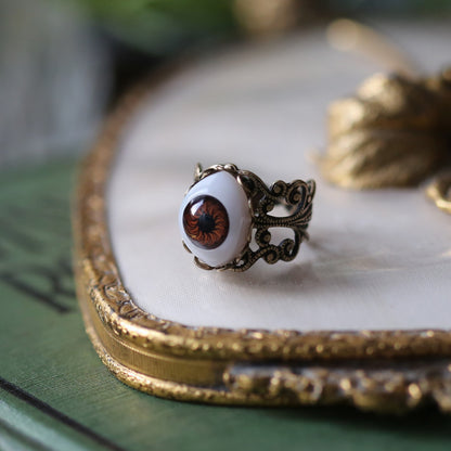 vintage style antiqued brass adjustable filigree ring with a brown oval all seeing eye in witchy style