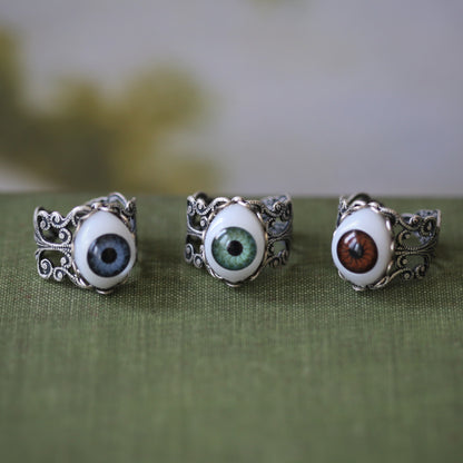 vintage style antiqued silver adjustable filigree ring with a green brown or blue oval evil eye in geeky zombie goth style