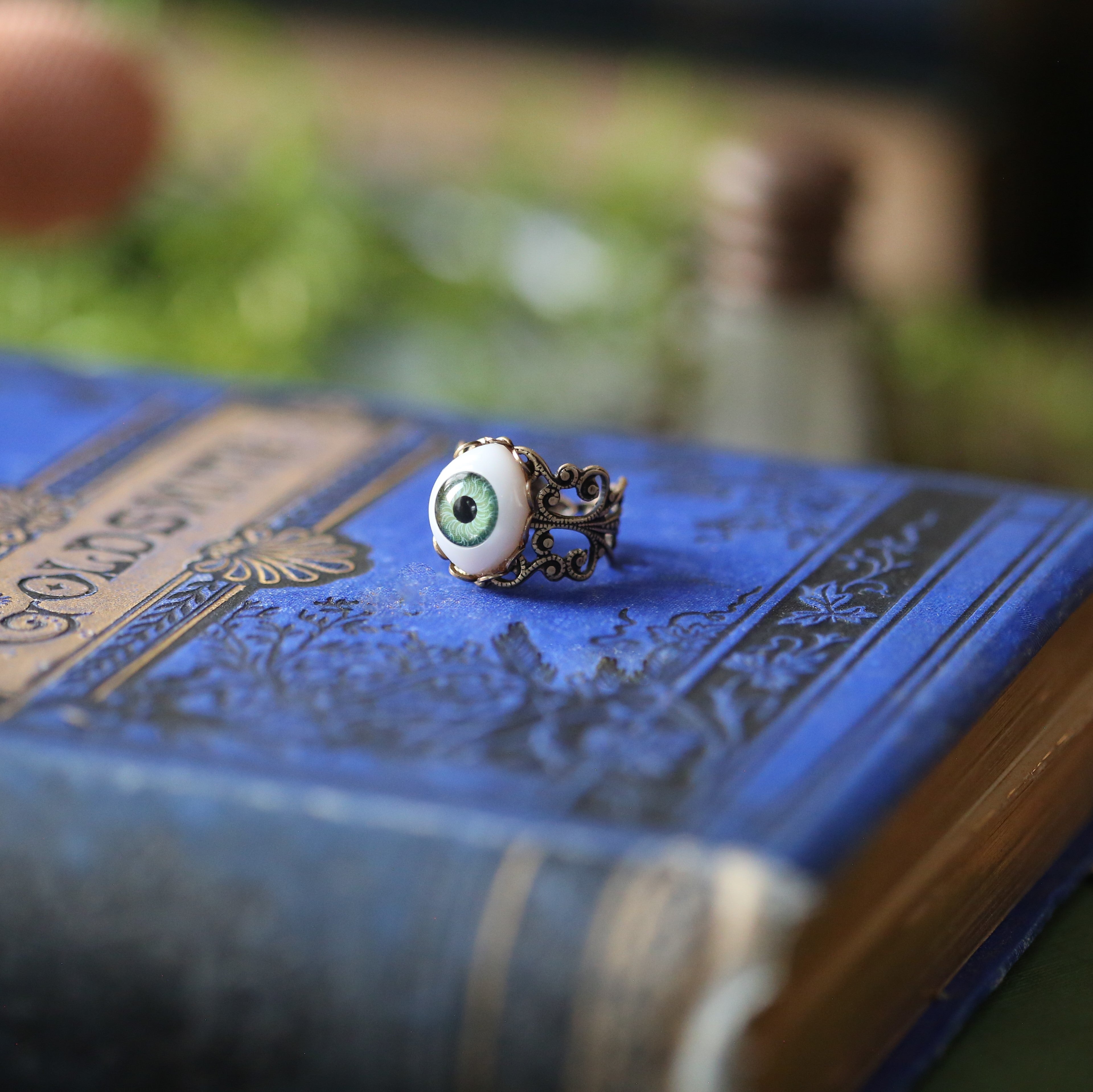 vintage style antiqued brass adjustable filigree ring with a green oval evil eye in aventurecore style